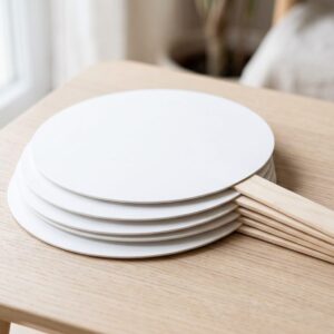 Stack of blank round handheld fans on wooden stick handles